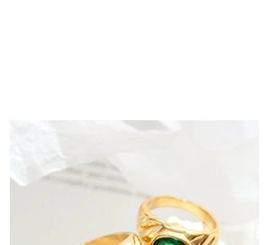Detailed macro shot of an elegant gold-plated ring with an oval green gemstone inlay