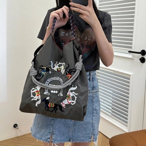 Close-up of colorful horse embroidery and woven rope handle on grey nylon tote bag