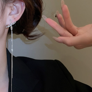 Détail de boucles d'oreilles pendantes argentées avec papillon portées par un mannequin