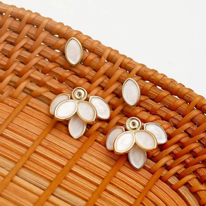 French vintage floral petal earrings set with white enamel and gold metal on woven mat