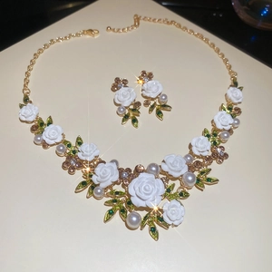 Detailed view of floral necklace and earrings set with pearls, crystals and gold leaves