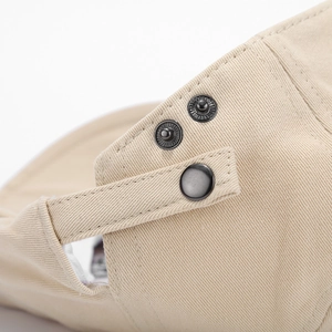 Detailed close-up of khaki cotton ivy cap with adjustable metal buckle strap