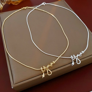 Dettaglio di collane a serpente in oro e argento su scatola marrone su superficie in legno