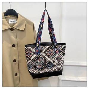 Close-up of geometric woven tote bag with red and blue patterns and black leather trim