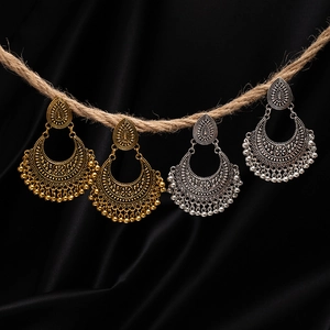 Macro shot of bohemian chandelier earrings with floral carvings and metal fringe on twine