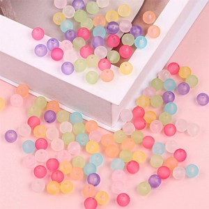 Matte colorful round acrylic beads for DIY jewelry making scattered on pink background