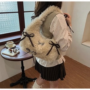 Detail of soft cream faux fur shoulder bag with brown ribbon bow on a model