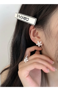 Detail of silver pearl flower ring and matching earring worn by a model