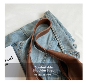 Detailed close-up of wide leather shoulder strap with brown pebble grain texture