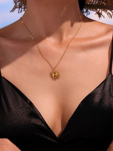 Close-up of golden sun goddess pendant necklace on model with warm natural lighting