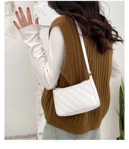 Detail of white quilted rhombic underarm bag with gold metal hardware and thin strap