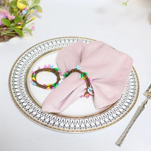 Close-up of colorful berry beaded napkin rings on white ceramic plate with floral decor