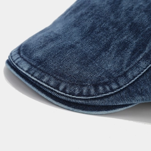 Détail macro du tissu denim délavé bleu foncé avec coutures renforcées et texture sergé