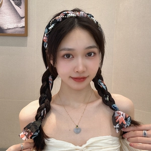 Detail of floral chiffon headband with pearls and heart pendant necklace on model