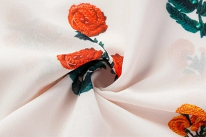Détail du tissu en mousseline avec motif réaliste de roses rouges et feuilles