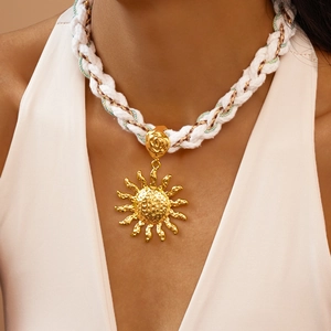 Detailed view of woven rope necklace with large gold sun pendant and flower clasp