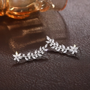 Detailed view of silver flower earrings with crystals on a luxury leather background