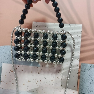 Macro shot of silver and black beaded crossbody bag with woven hollow square pattern