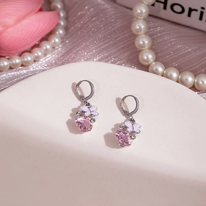 Détail de boucle d'oreille en cristal rose avec papillon blanc sur plateau chic