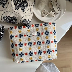 Detail of floral embroidery on a cream canvas makeup bag with a minimalist aesthetic