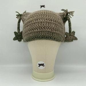 Macro detail of hand-knitted cat ear hat with earthy tones and star tassel pendants