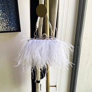 Detailed close-up of white ostrich feather evening bag with a gold metal ring handle