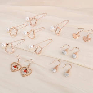 Detailed view of rose gold heart and geometric earrings on elegant pleated silk fabric