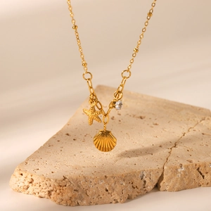 Detailed close-up of golden starfish and shell pendants with a sparkling zircon accent