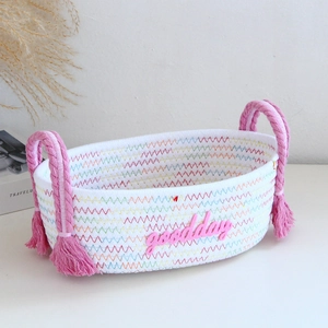 Close-up of a white woven cotton rope basket with goodday lettering and pink tassel handles