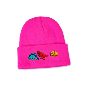 Close-up of bright pink knitted hat featuring colorful cartoon dinosaur embroidery