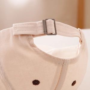 Close-up of beige cotton baseball cap featuring metal buckle and bear embroidery details
