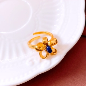 Macro detail of vintage bow ring with blue oval stone and matte gold finish