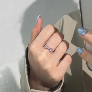 Close-up of S925 silver bow ring with pink heart stones and micro-pave zircons on a finger