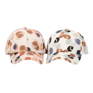Detail of floral print baseball caps in beige and pink tones with watercolor dot patterns