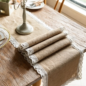 Detail of natural jute table runner featuring delicate white lace trim on wooden table