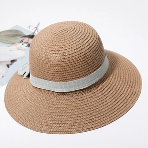 Detail of wide brim straw sun hat with light green plaid ribbon and delicate bow accent
