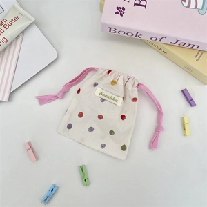 Close-up of cream cotton drawstring bag with colorful polka dots and pink cords
