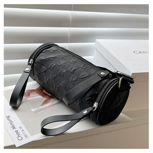 Close-up of quilted cylinder shoulder bag with metal zipper and leather strap