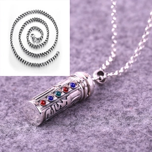 Detailed macro view of an engraved silver Buddhist pendant with colorful gemstone inlays