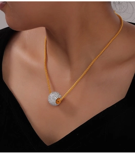 Dettaglio della collana in titanio dorato con pendente a sfera di cristalli su modella