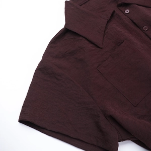 Detail view of the shirt collar and front pocket on a dark brown linen-blend romper
