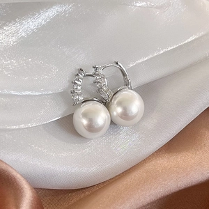 Elegant silver pearl earrings with zircon inlay displayed on a luxurious silk background