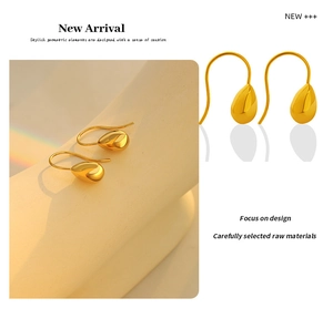 Detail showing elegant gold teardrop earrings with smooth polished metallic finish