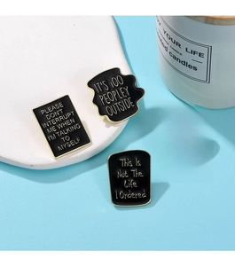 Detailed view of four black enamel and gold zinc alloy brooches with quotes