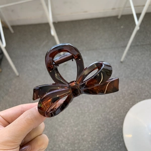 Detailed close-up of dark amber tortoiseshell bow hair claw clip with sturdy metal spring