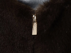 Detailed macro view of high-quality metal zipper on dark brown faux fur aviator jacket
