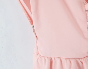 Dettaglio di abito rosa con cerniera invisibile laterale e finiture plissettate