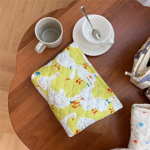 Close-up of yellow quilted cotton makeup bag with duck print on a wooden table