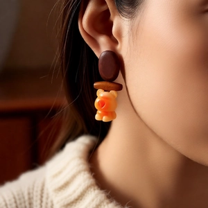 Detail of wooden bear drop earrings on model in cozy knit sweater and warm lighting