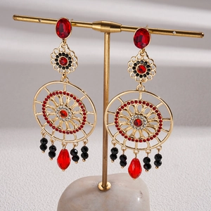 Detailed view of vintage gold hollow flower earrings with red crystal teardrop pendants